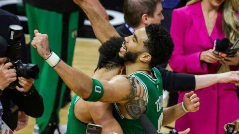 Jayson Tatum (derecha) y Derrick White, de los Boston Celtics, celebran la canasta ganadora en la cancha de los Miami Heat.