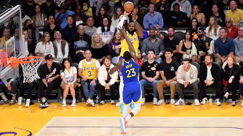LeBron James, de los Lakers, lanza a canasta, presionado por Draymond Green, de los Golden State Warriors.