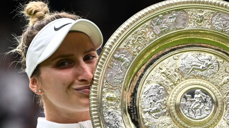 La checa Marketa Vondrousova besa el trofeo que le acredita como campeona del torneo de Wimbledon, después de vencer en la final a la tunecina Ons Jabeur.