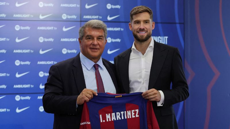 El presidente del Barcelona, Joan Laporta, le entrega la camisa al defensa Iñico Martínez.