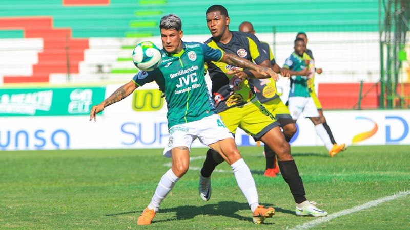 El delantero uruguayo del Marathón, Nicolás Royón, cubre el balón ante la marca de Óscar González.