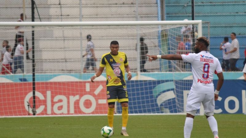 Sergio Peña sale con balón dominado frente al delantero Jorge Benguché.