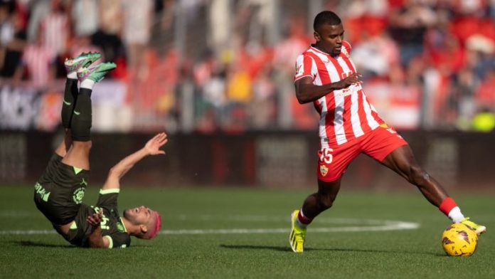 El defensor brasileño de Girona, Yan Couto, cae mientras el defensor español de Almería, Sergio Akieme, controla el balón.