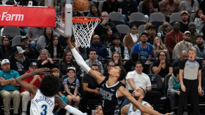 El delantero francés de San Antonio Spurs, Victor Wembanyama, hace una bandeja pasó el centro francés de Minnesota Timberwolves, Rudy Gobert.