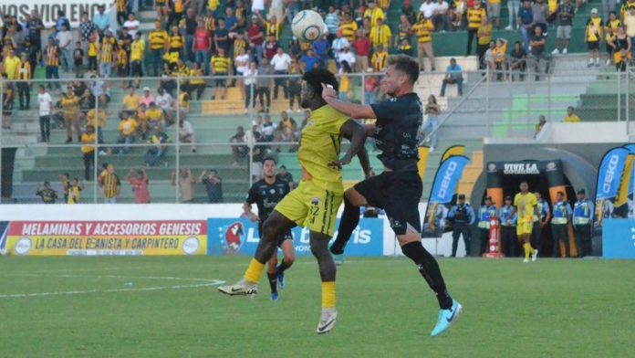 El delantero del Génesis Comayagua, Marlon "Machuca" Ramírez, y el defensa del Real España, Sebastián Hernández, saltan por el balón.