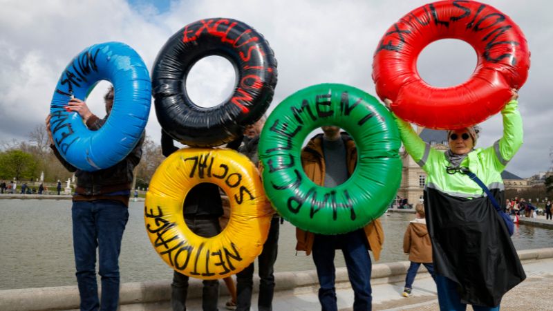 Activistas del colectivo "Le revers de la medaille" (la otra cara de la moneda) muestran boyas inflables en el Jardín de Luxemburgo en París durante una manifestación para llamar la atención sobre la desigualdad social exacerbada por los próximos Juegos Olímpicos de París 2024.