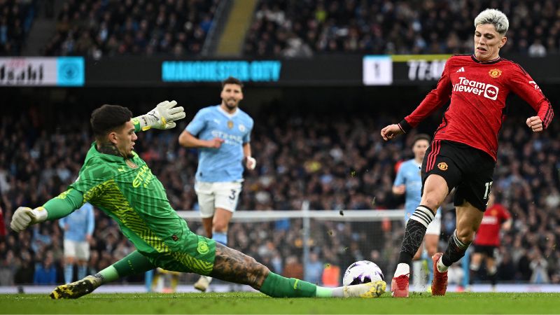 El portero brasileño del Manchester City, Ederson, se enfrenta al centrocampista argentino del Manchester United, Alejandro Garnacho.