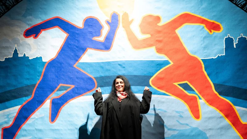 La novelista gráfica e ilustradora franco-iraní Marjane Satrapi posa frente a la parte central de un tapiz tríptico olímpico creado para los Juegos Olímpicos de París 2024.