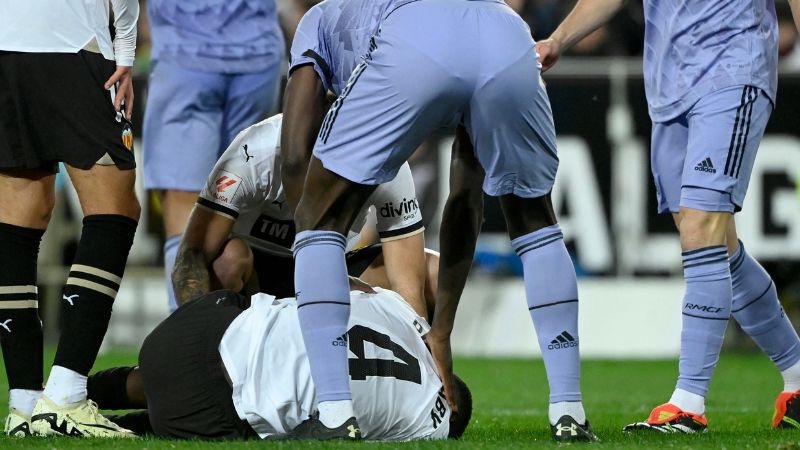 El defensor guineano del Valencia, Mouctar Diakhaby, herido yace en el suelo durante el partido contra el Real Madrid.