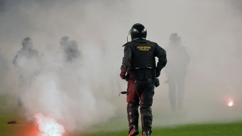 Agentes de policía croatas caminan por el campo durante enfrentamientos con miembros de la ultra fanática del equipo de fútbol Hajduk Split.