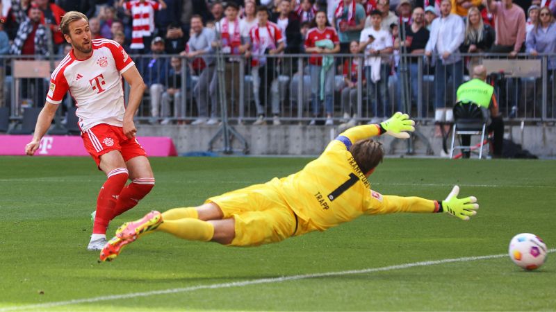 El delantero inglés del Bayern Munich Harry Kane, anota el gol inicial pasando al portero alemán Kevin Trapp de Frankfurt.