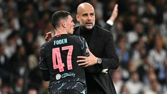 El centrocampista inglés del Manchester City, Phil Foden, habla con el técnico español Pep Guardiola.