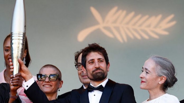 El guionista y director francés Mickael Gamrasni sostiene la antorcha olímpica junto a la directora ejecutiva de France Televisions, Delphine Ernotte.