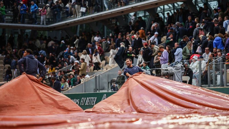 El personal del torneo cubre la cancha Simonne-Mathieu debido a la lluvia mientras los partidos se retrasan en el quinto día del Roland Garros.