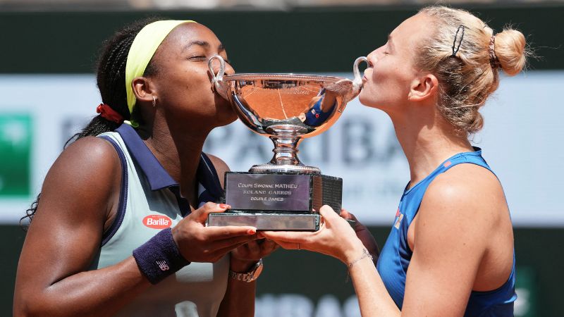 La estadounidense Coco Gauff y la checa Katerina Siniakova besan el trofeo ganado en dobles.