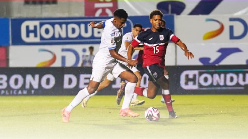 El capitán hondureño, Anthony Lozano, conduce el balón ante la mirada del cubano Yunior Pérez.