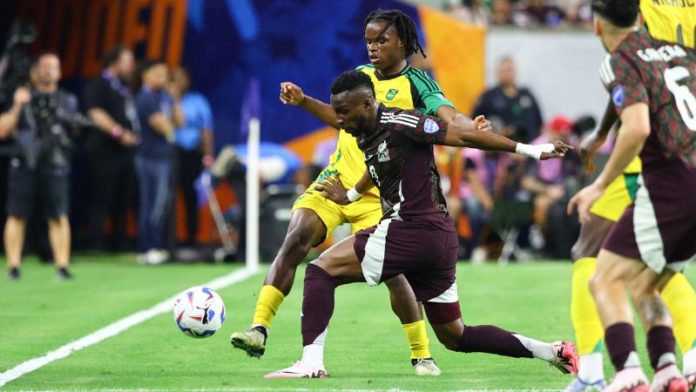 El delantero de México Julián Quiñones compite por el balón con el defensor de Jamaica Dexter Lembikisa.