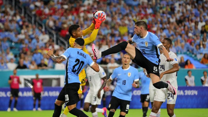 El mediocampista uruguayo Federico Valverde levanta la pierna en busca del balón que controla el portero panameño, Orlando Mosquera.