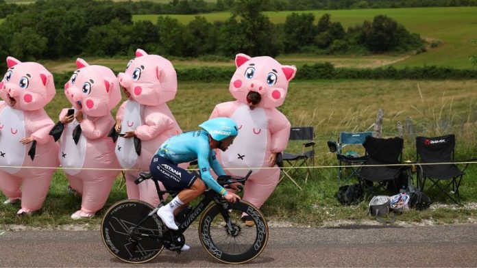 El ciclista británico Mark Cavendish del equipo Astana Qazaqstan pasa en bicicleta entre los espectadores con disfraces inflables.