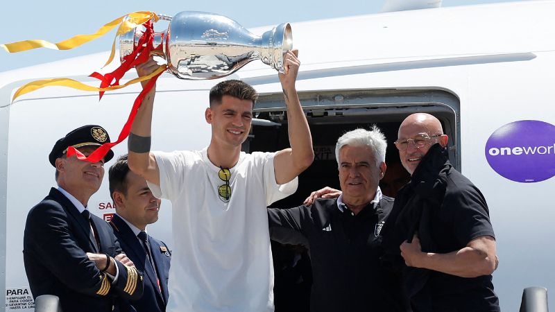 El delantero español Álvaro Morata, el presidente de la Federación Española de Fútbol, ​​Pedro Rocha, y el seleccionador español, Luis de la Fuente, posan junto al personal de la aerolínea con el trofeo de la Eurocopa 2024.