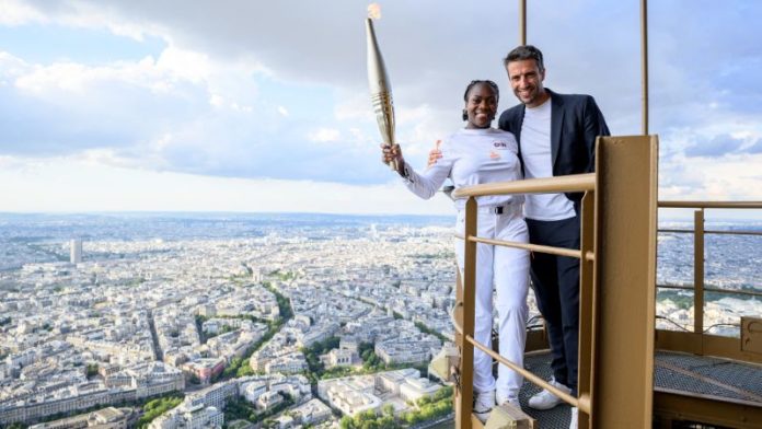 La judoca francesa Clarisse Agbegnenou sosteniendo la antorcha olímpica junto al presidente francés del Comité Organizador de los Juegos Olímpicos y Paralímpicos de París 2024, Tony Estanguet, en la Torre Eiffel.