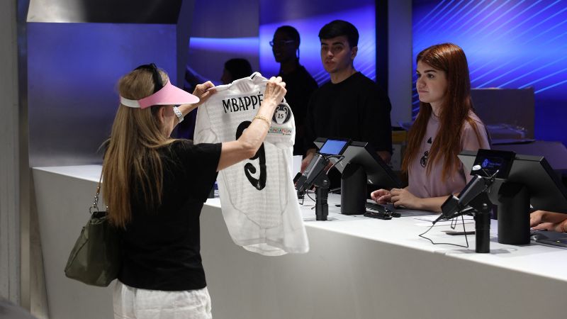 Una mujer compra la camiseta recién lanzada del futbolista francés Killyan Mbappé.