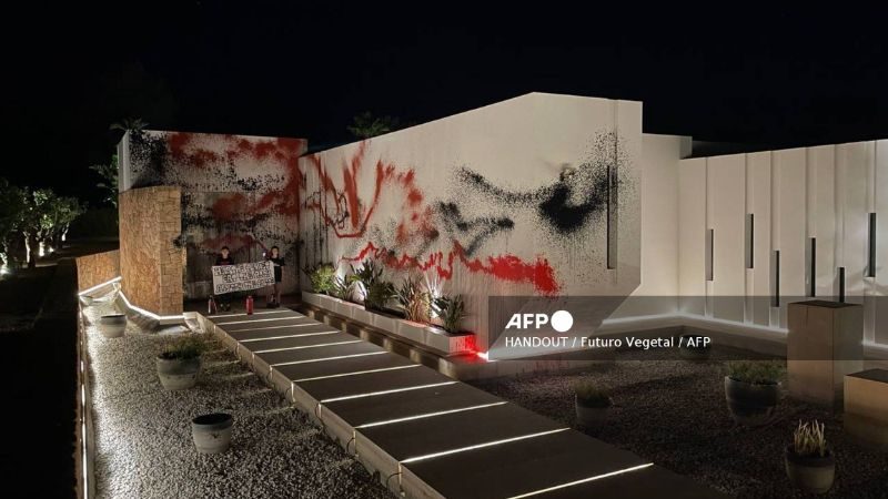 El colectivo de desobediencia civil Futuro Vegetal muestra a dos activistas sosteniendo una pancarta que dice "Ayuden al planeta, coman a los ricos, abolan a la policía" después de pintar con aerosol la casa de la estrella del fútbol argentino Lionel Messi en Ibiza.