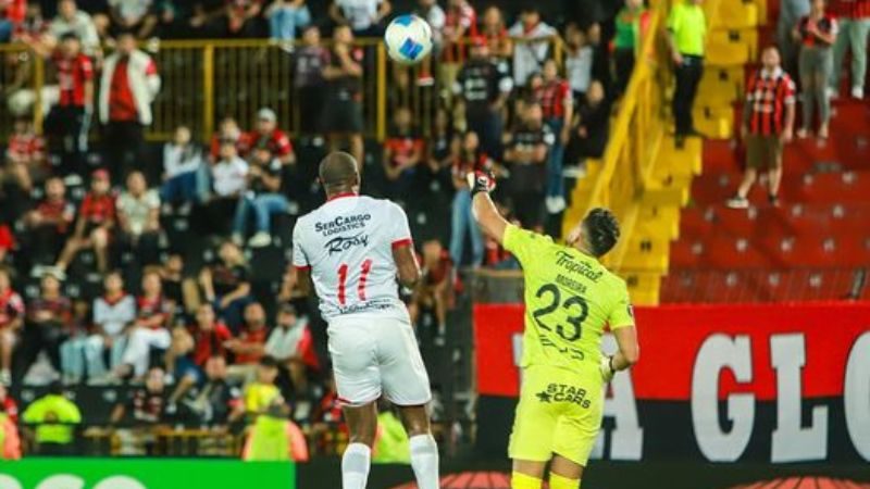 El ecuatoriano Juan Anangonó salta por el balón con el portero de la Liga Deportiva Alajuelense, Leonel Moreira.