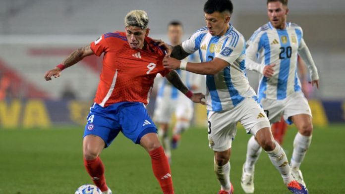 El delantero chileno Carlos Palacios y el defensa argentino Lisandro Martínez luchan por el balón.