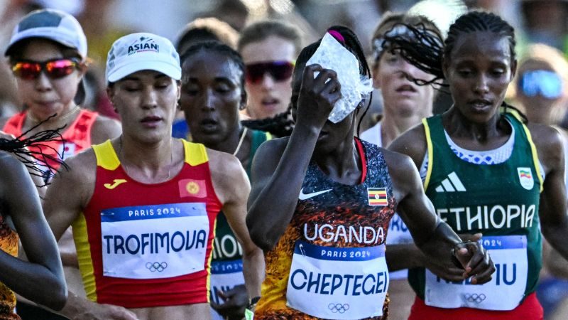 Rebecca Cheptegei (centro) de Uganda se aplica una bolsa de hielo en la cabeza mientras compite en el maratón femenino de los Juegos Olímpicos de París 2024.