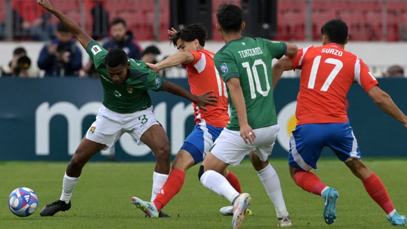 El defensa de Bolivia Diego Medina y el mediocampista de Chile Víctor Dávila luchan por el balón.