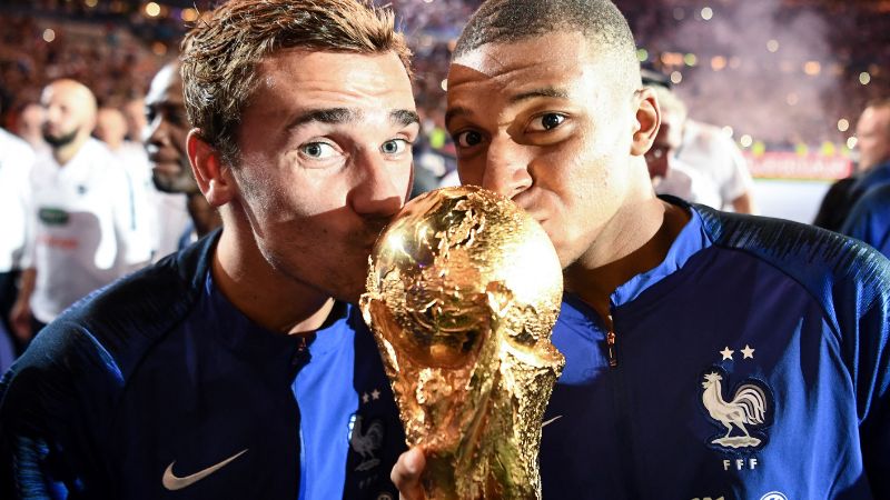 Antoine Griezmann y el Kylian Mbappé besan el trofeo de la Copa Mundial de 2018.