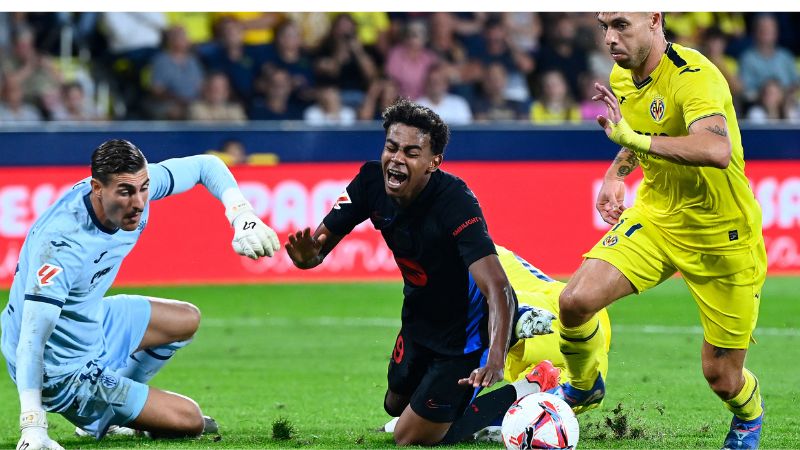 El delantero español del Barcelona, ​​Lamine Yamal, lucha por el balón con el portero español del Villarreal, Diego Conde, y el defensa, Kiko Femenia.