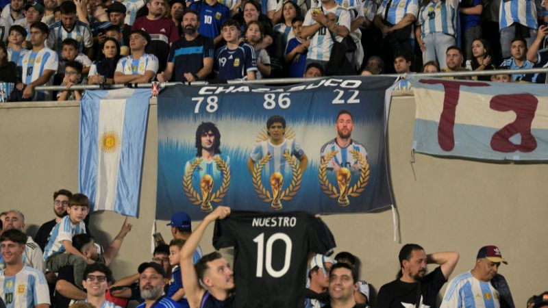 Una bandera con imágenes del ex delantero argentino Mario Kempes, la leyenda Diego Maradona y Lionel Messi.