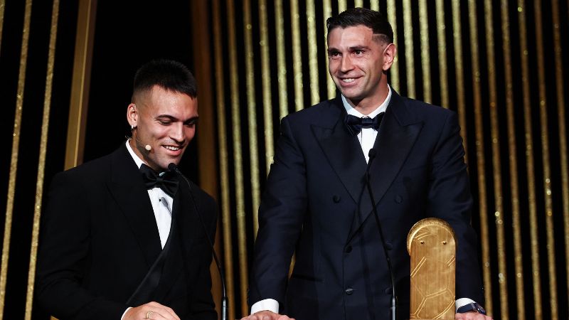 El portero argentino del Aston Villa, Emiliano Martínez, recibe el Trofeo Yashin de manos de su compatriota del Inter de Milán, Lautaro Martínez.