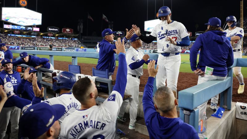 Shohei Ohtani, de los Dodgers de Los Ángeles, es felicitado por sus compañeros de equipo en el dugout durante el sexto juego de la Serie de Campeonato de la Liga Nacional contra los Mets de Nueva York.