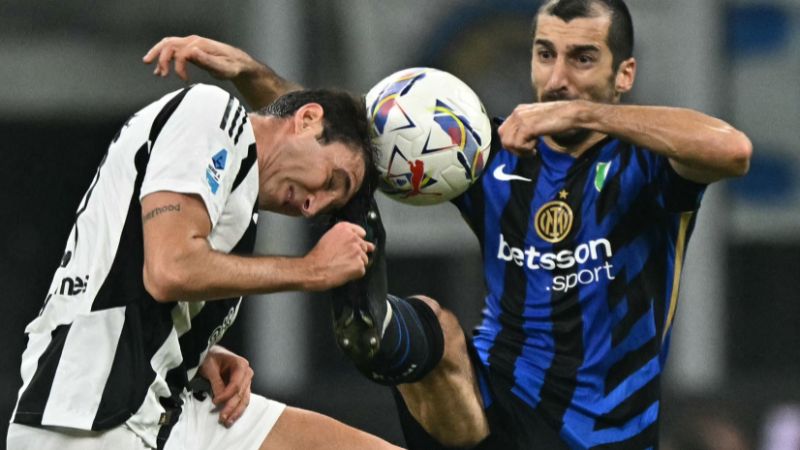 El defensa italiano de la Juventus, Andrea Cambiaso, lucha por el balón con el mediocampista armenio del Inter de Milán, Henrikh Mkhitaryan.