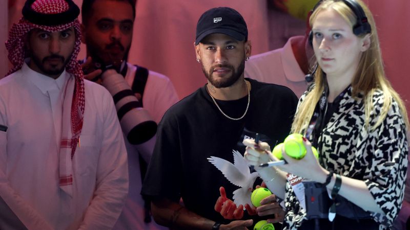 El futbolista brasileño Neymar del Al-Hilal saudí sostiene pelotas de tenis mientras espera felicitar al español Carlos Alcaraz después de ganar el partido de tenis de cuartos de final contra el danés Holger Rune en el torneo de exhibición "6 Kings Slam" en Riad.