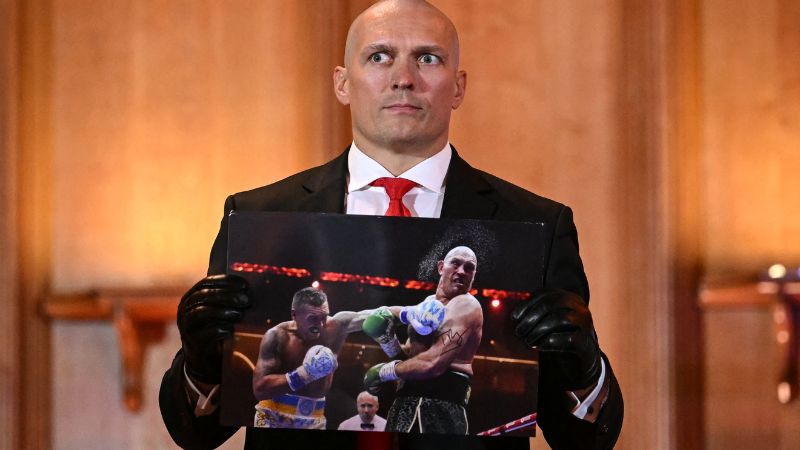 El ucraniano Oleksandr Usyk sostiene una fotografía firmada por el británico Tyson Fury durante una conferencia de prensa en el centro de Londres.