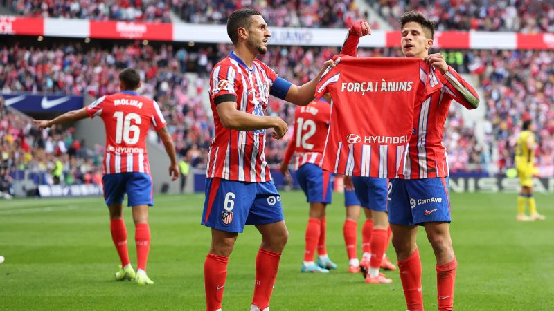 El delantero argentino del Atlético de Madrid, Giuliano Simeone, sostiene una camiseta en apoyo a las víctimas de las inundaciones en Valencia.