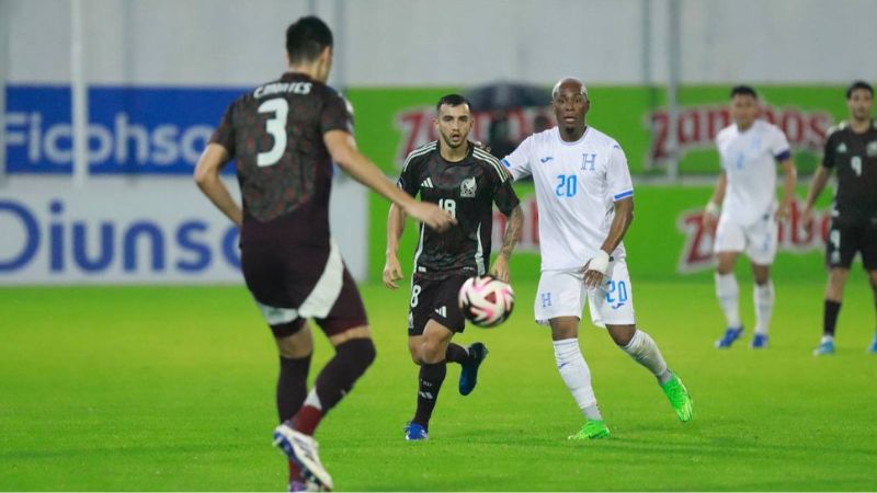 Deybi Flores observa al defensa mexicano César Montes que se apresta a despejar el balón.