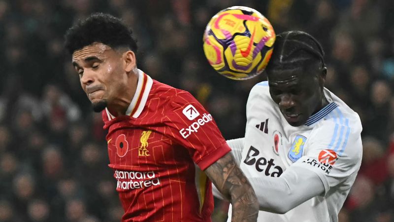 El defensa belga del Aston Villa, Amadou Onana, cabecea el balón para despejarlo bajo la presión del centrocampista colombiano del Liverpool, Luis Díaz.