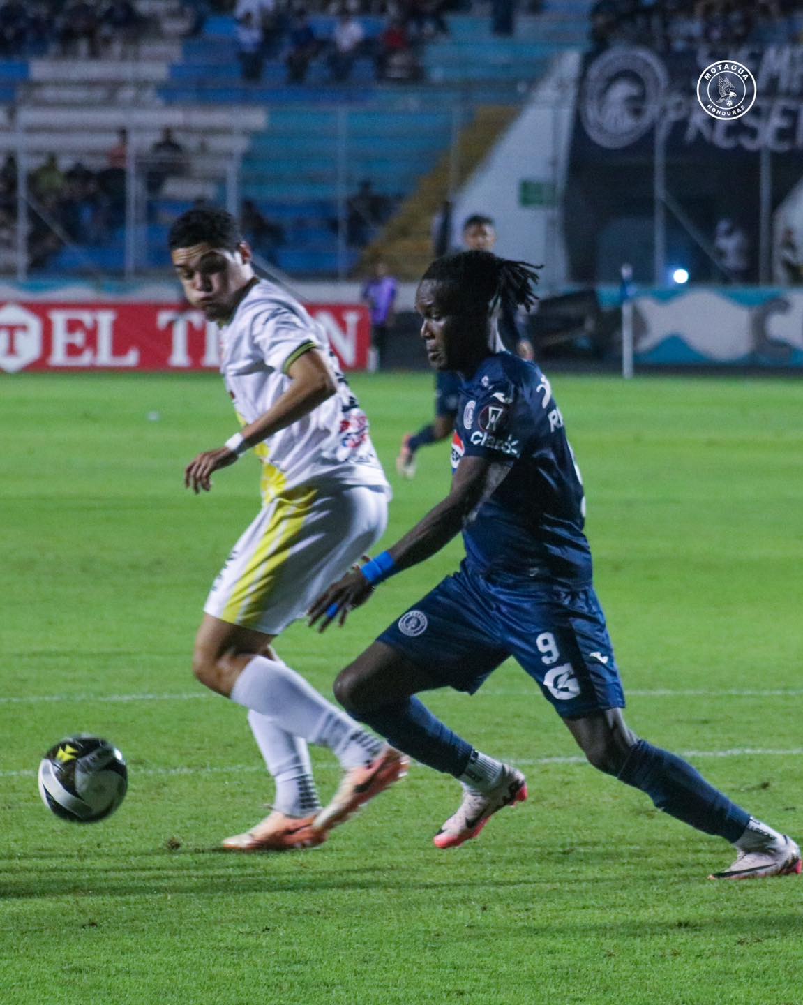 Rubilio Castillo le gana la posición al defensa de Génesis Comayagua, Junior García.