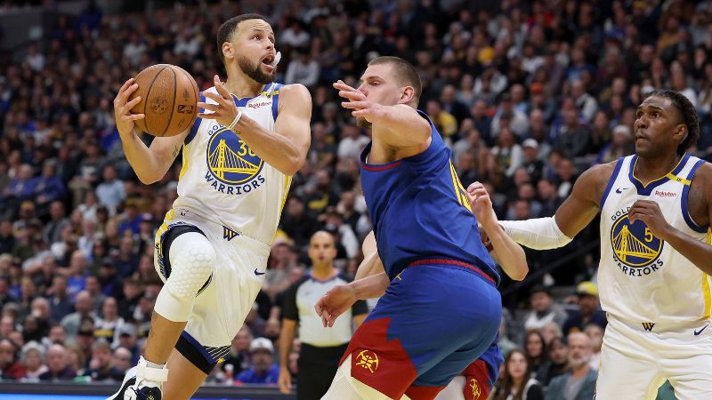 Stephen Curry de los Golden State Warriors conduce contra Nikola Jokic de los Denver Nuggets.