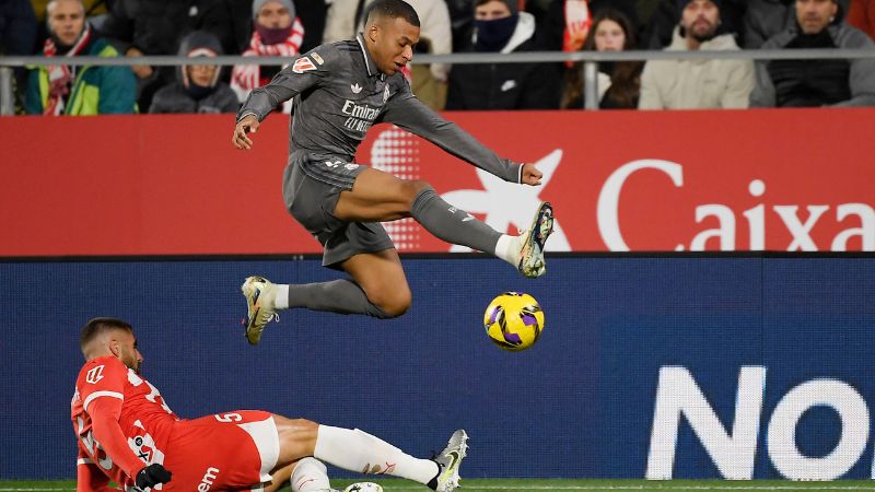 El delantero francés del Real Madrid, Kylian Mbappe, y el defensa español del Girona, David López, compiten por el balón.