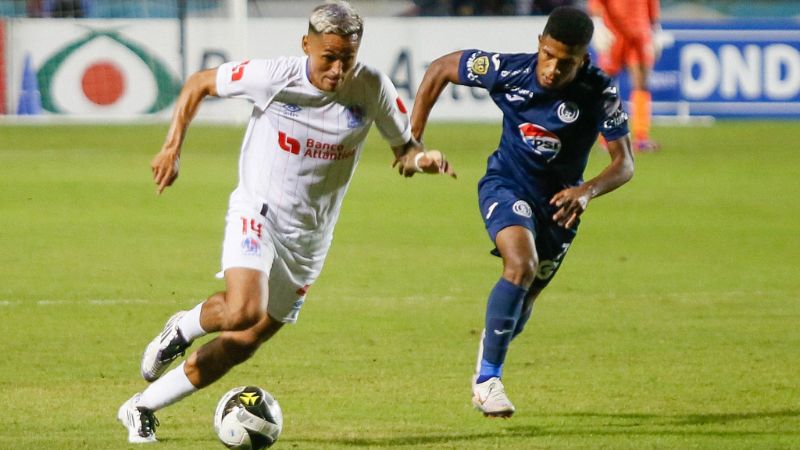 Andy Najar, de Olimpia, se lleva el balón presionado por Jorge Serrano, de Motagua.