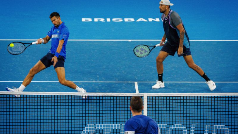 El australiano Nick Kyrgios y el serbio Novak Djokovic devuelven el balón durante su partido de dobles masculino contra el australiano Alexander Erler y el alemán Andreas Mies en el torneo internacional de Brisbane.