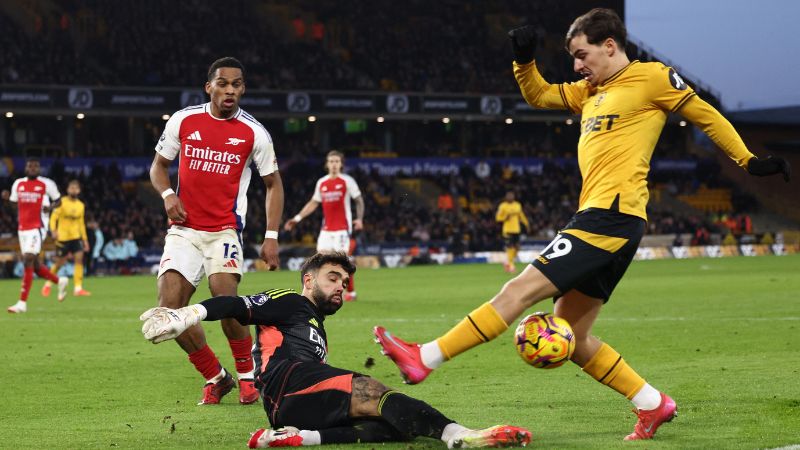 El guardameta español del Arsenal, David Raya, salva el balón a los pies del centrocampista portugués del Wolverhampton Wanderers, Rodrigo Gomes.