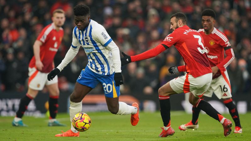 El centrocampista camerunés del Brighton, Carlos Baleba, lucha por el balón con el defensa marroquí del Manchester United, Noussair Mazraoui.