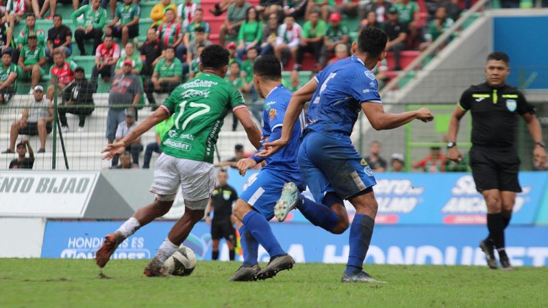 El volante de Marathón, Alexy Vega, conduce el balón marcado por Diego Rodríguez, de Victoria.